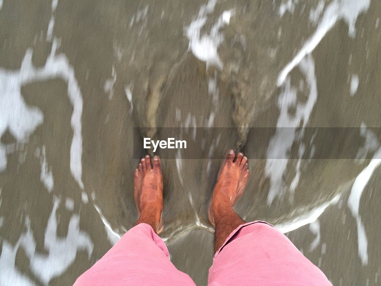 Low section of man standing at beach