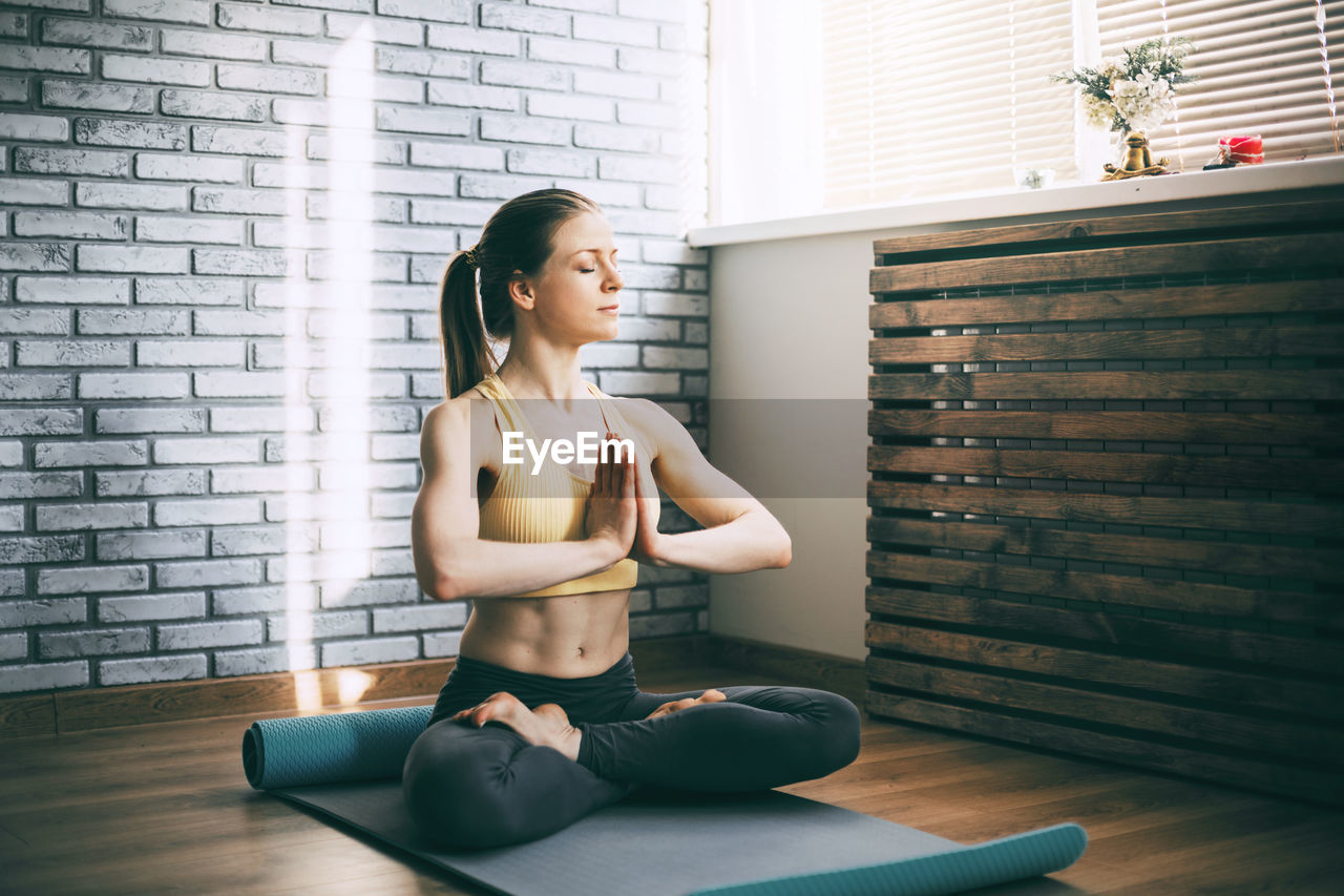 Full length of woman meditating at home