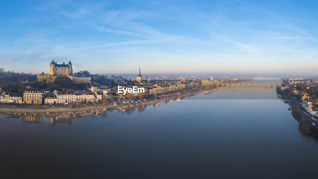 Saumur skyline with medieval castle, saint peter church and river at sunrise, loire valley, france