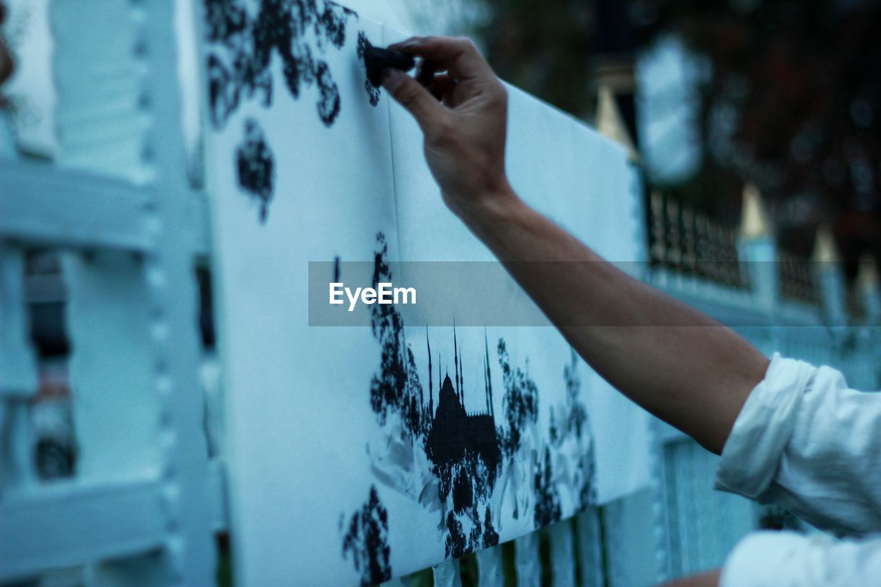 Cropped image of artist painting on fence
