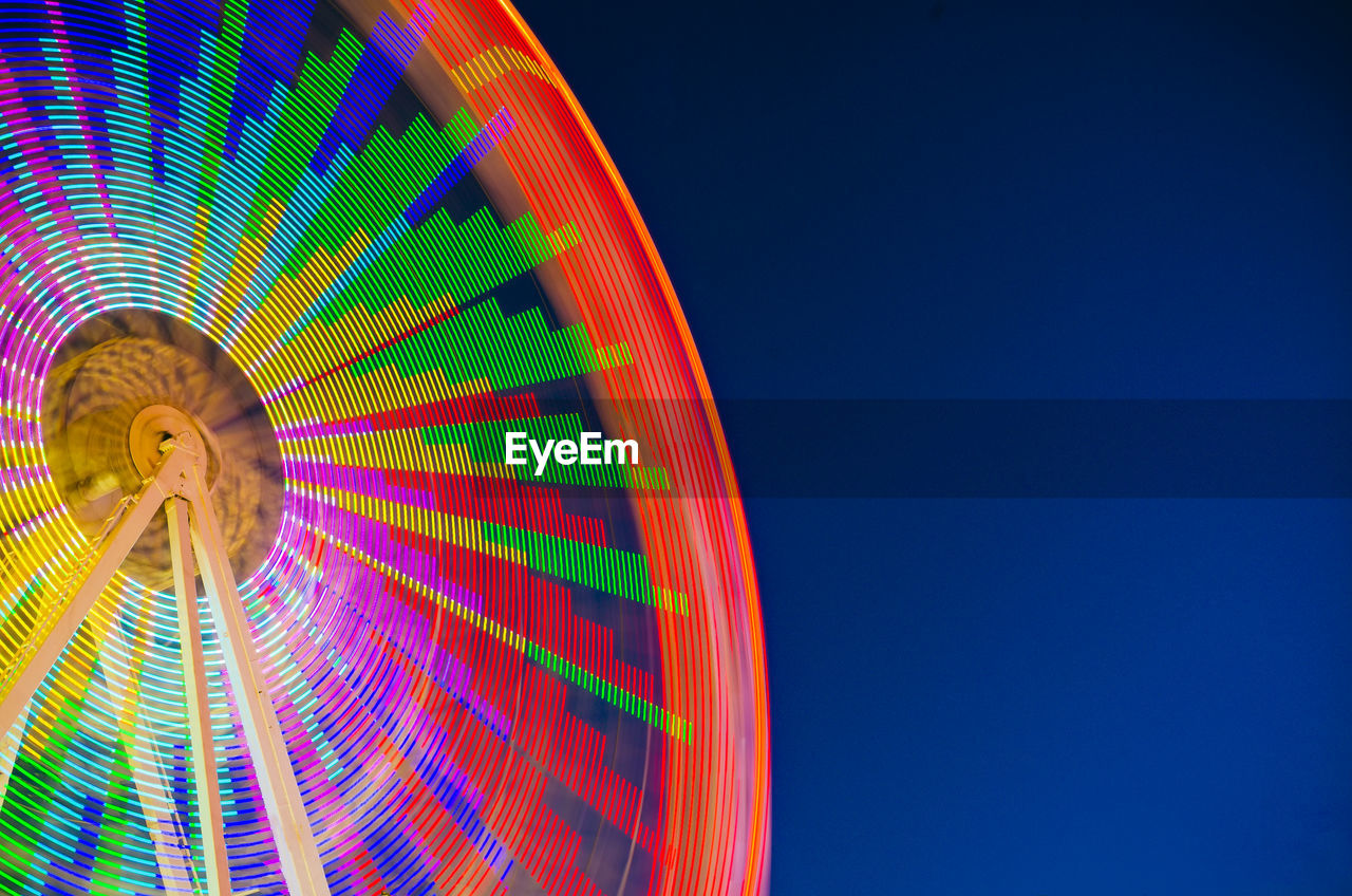 Low angle view of colorful ferris wheel against clear sky at night