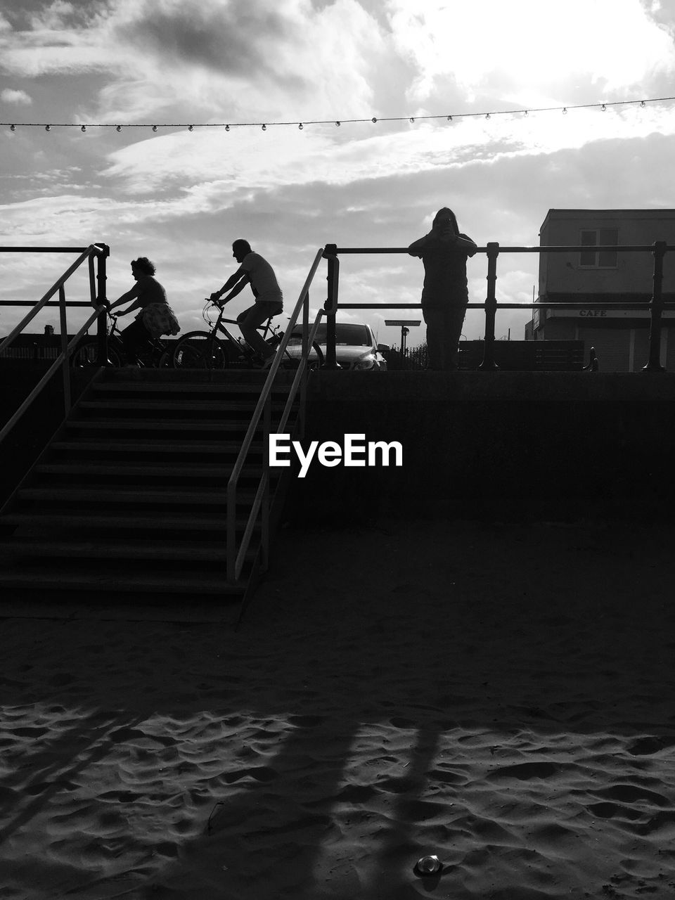 Silhouette people on steps by sea against sky