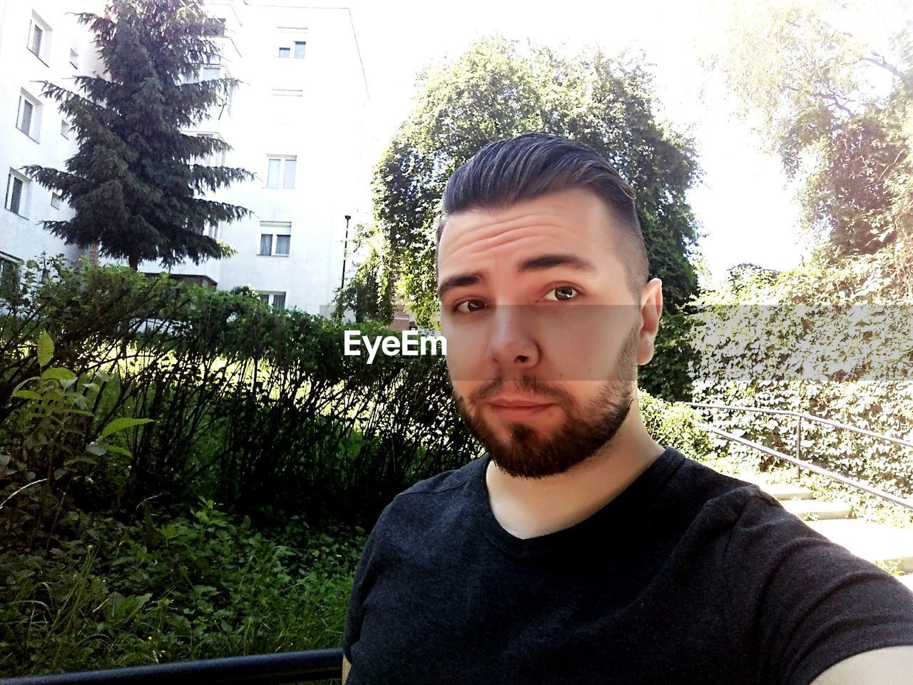 Portrait of bearded young man against trees