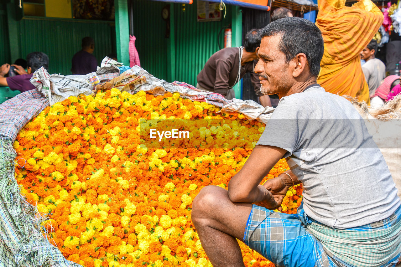 REAR VIEW OF PEOPLE SITTING AT MARKET