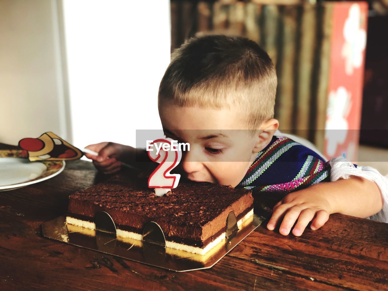 Boy eating birthday cake at table