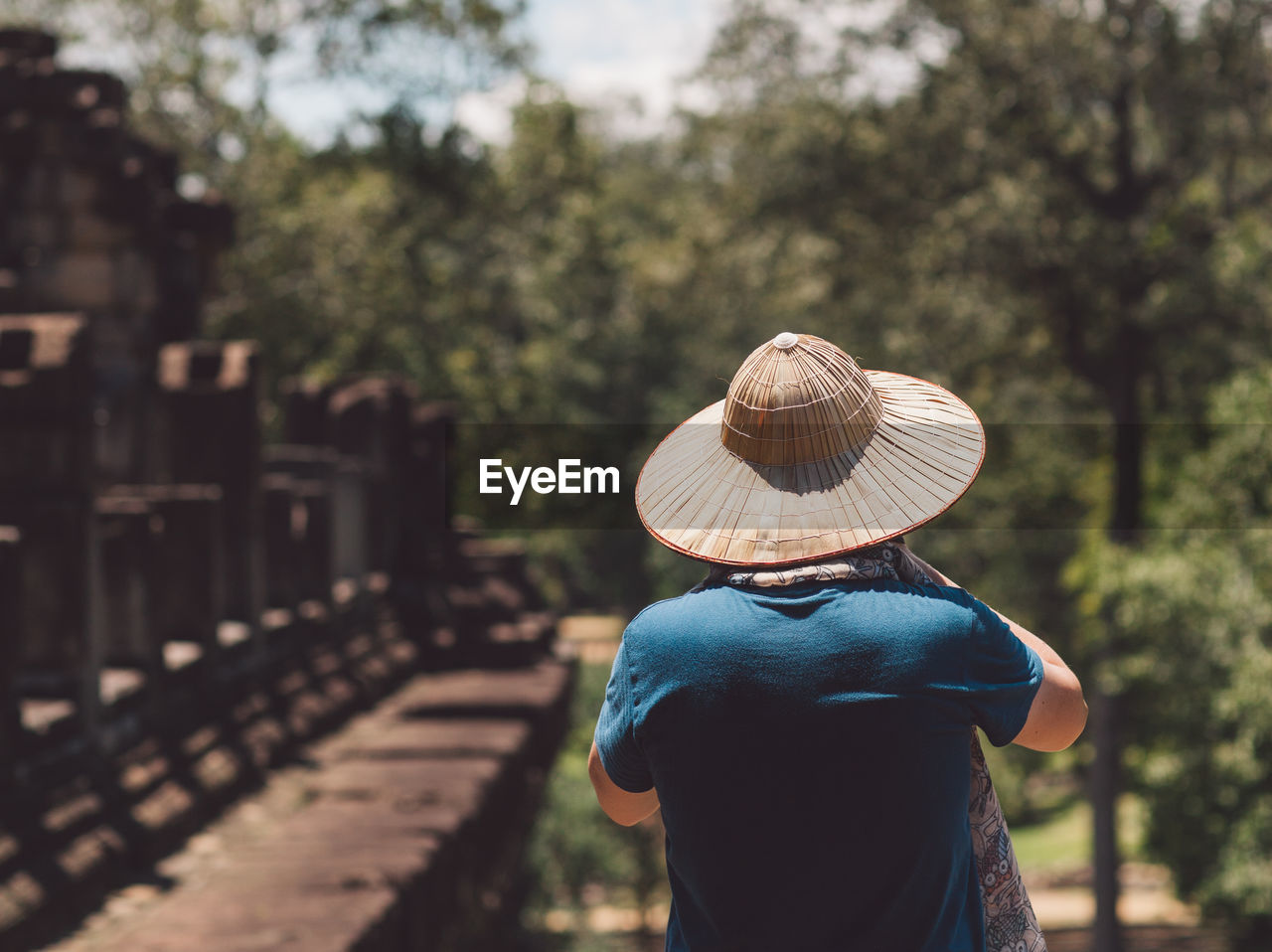 Rear view of man wearing hat standing in park during sunny day