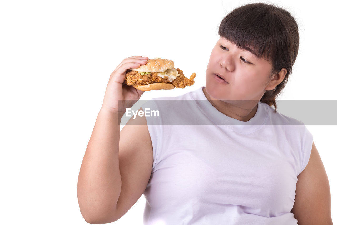 MIDSECTION OF BOY HOLDING ICE CREAM OVER WHITE BACKGROUND