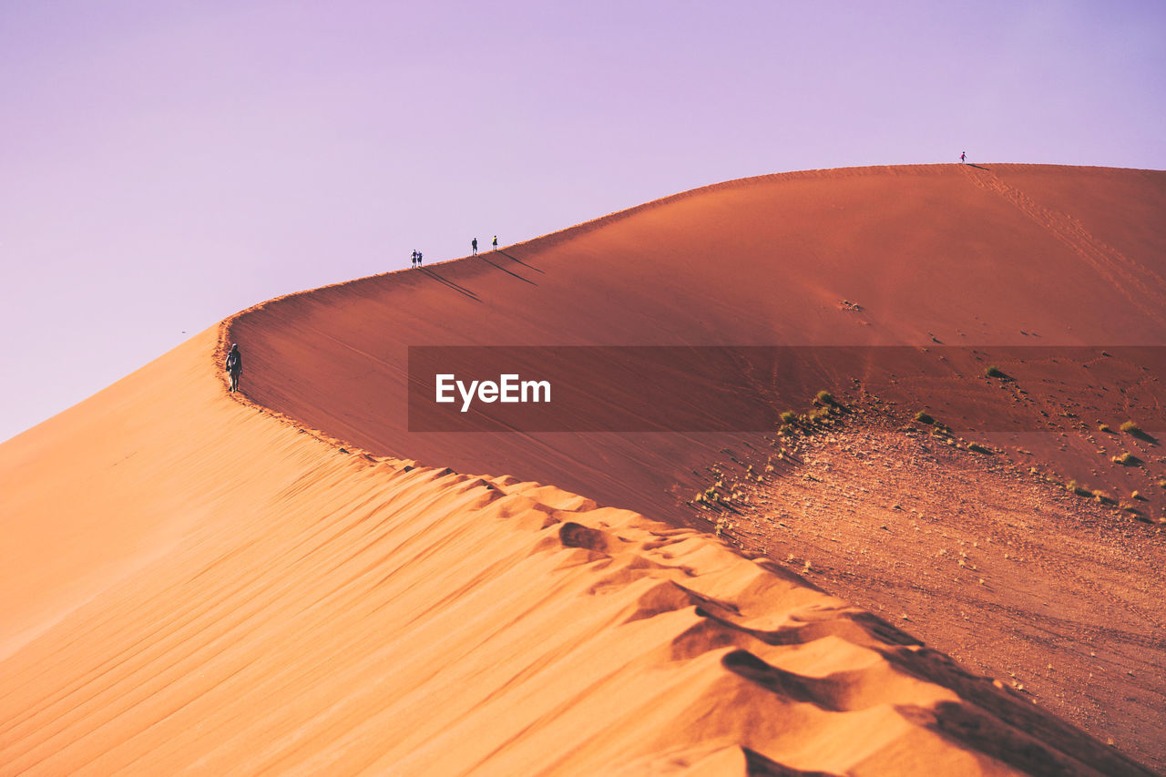 People climbing the sand dunes of sossusvlei in namibia