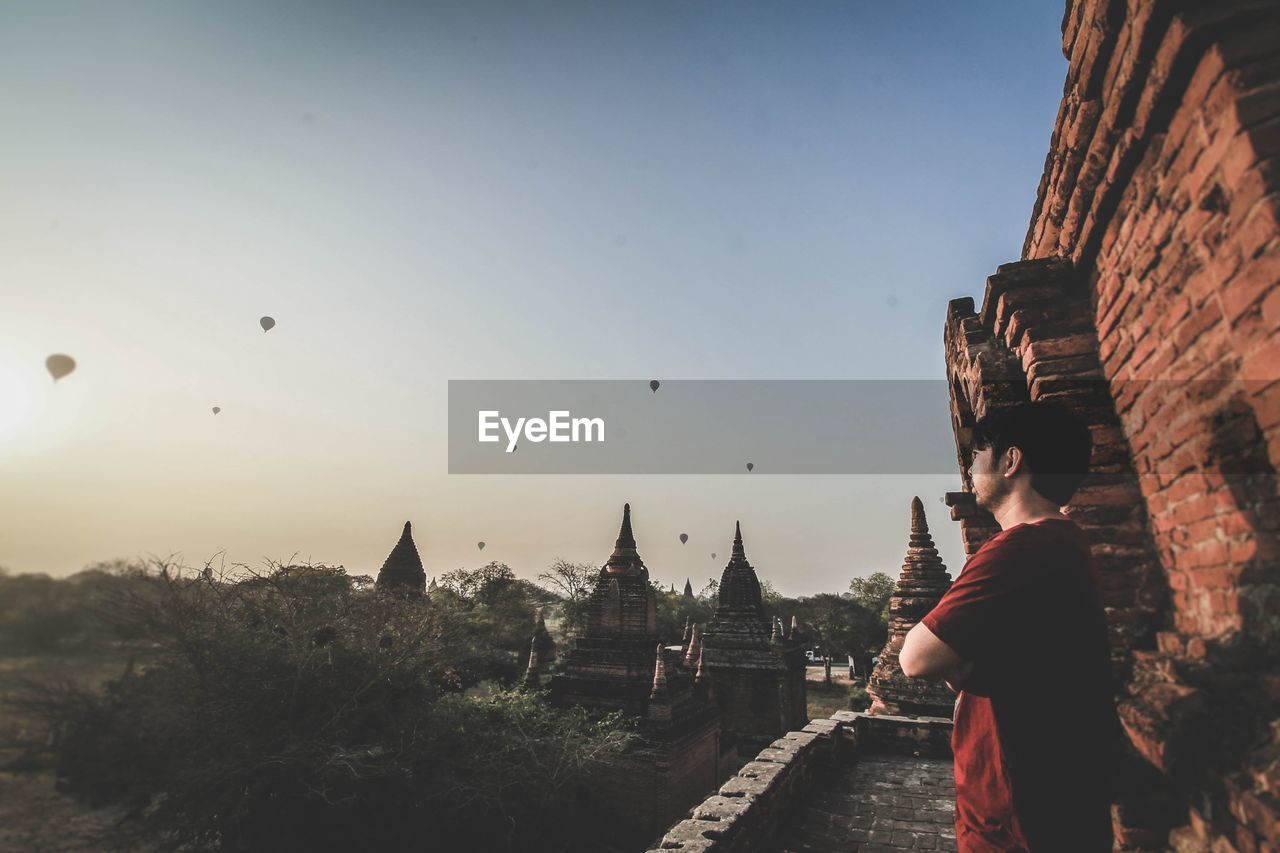 Man looking at hot air balloons against clear sky