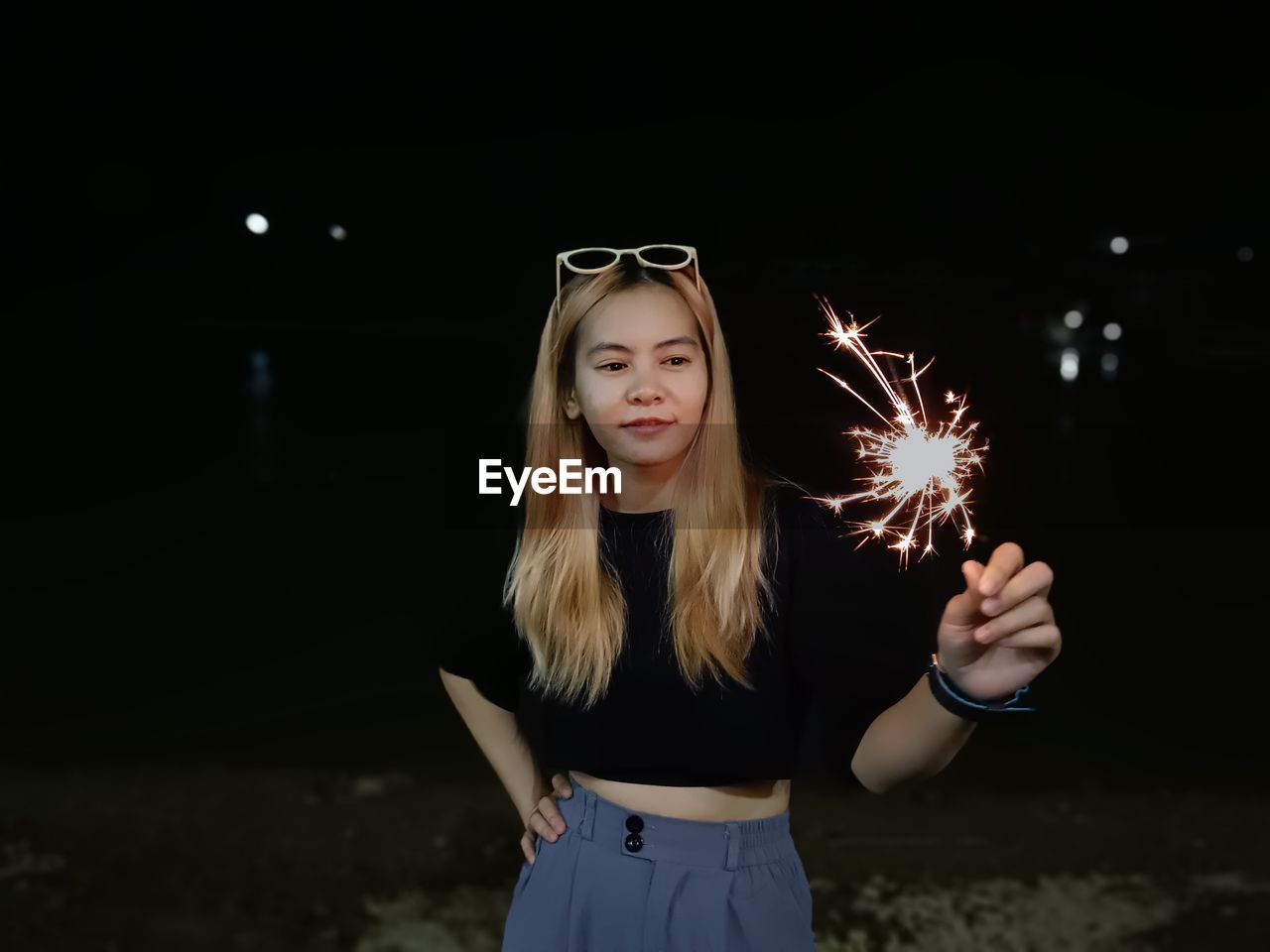 Portrait of young woman holding sparkler at night