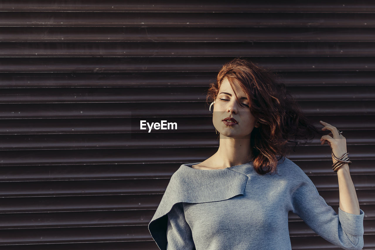 Beautiful young woman standing against shutter