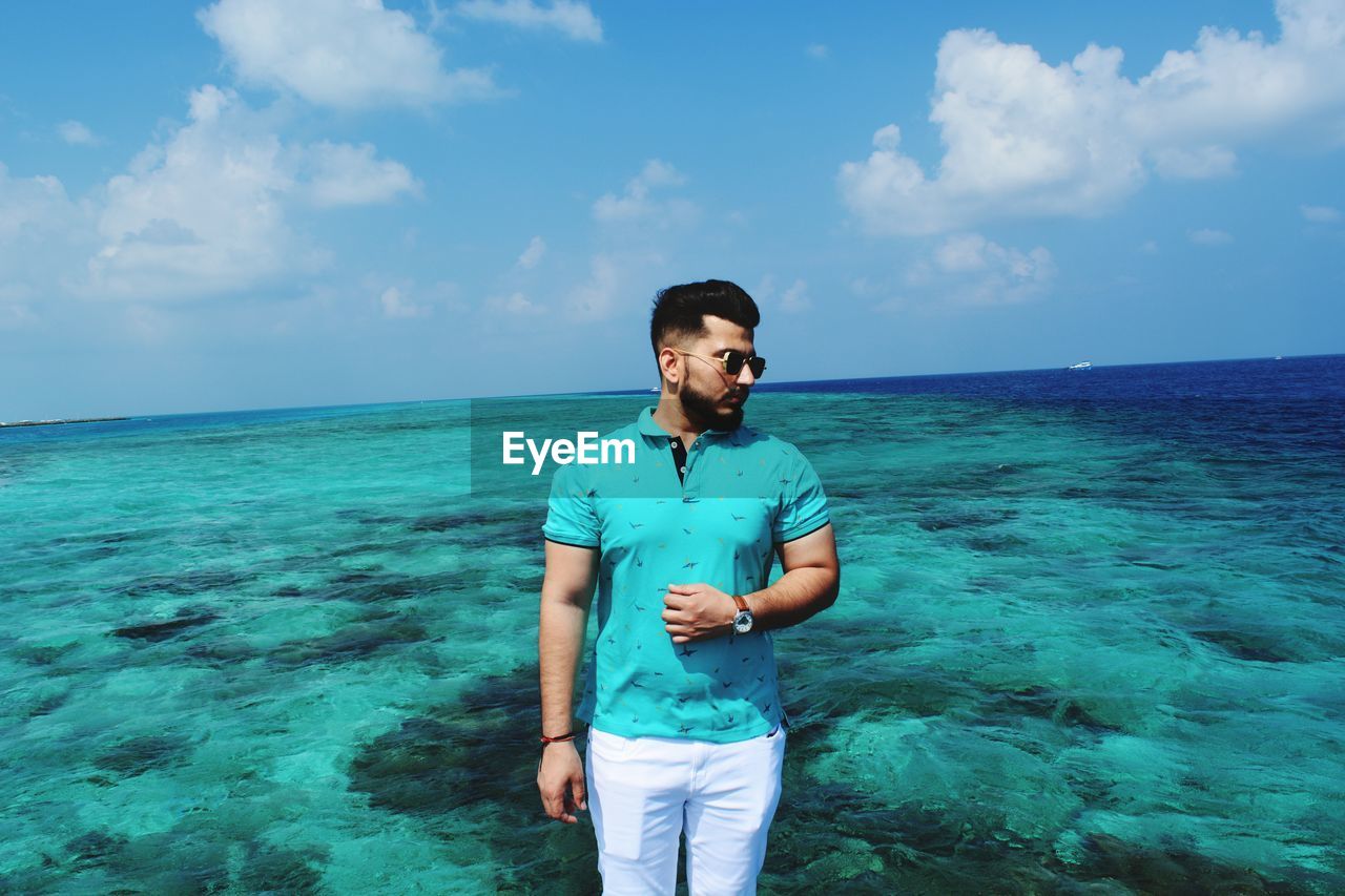 YOUNG MAN STANDING AGAINST SEA