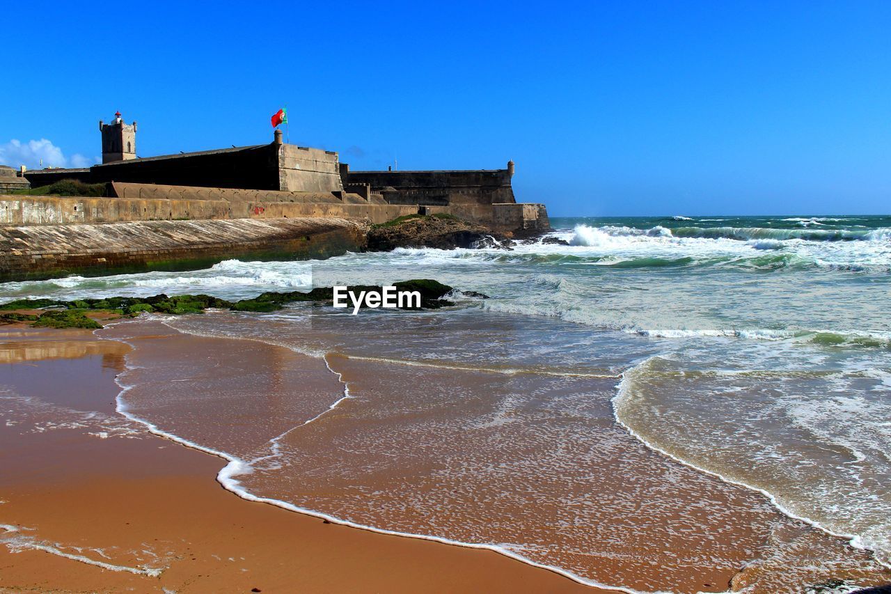 Waves reaching on shore by fort of sao juliao da barra