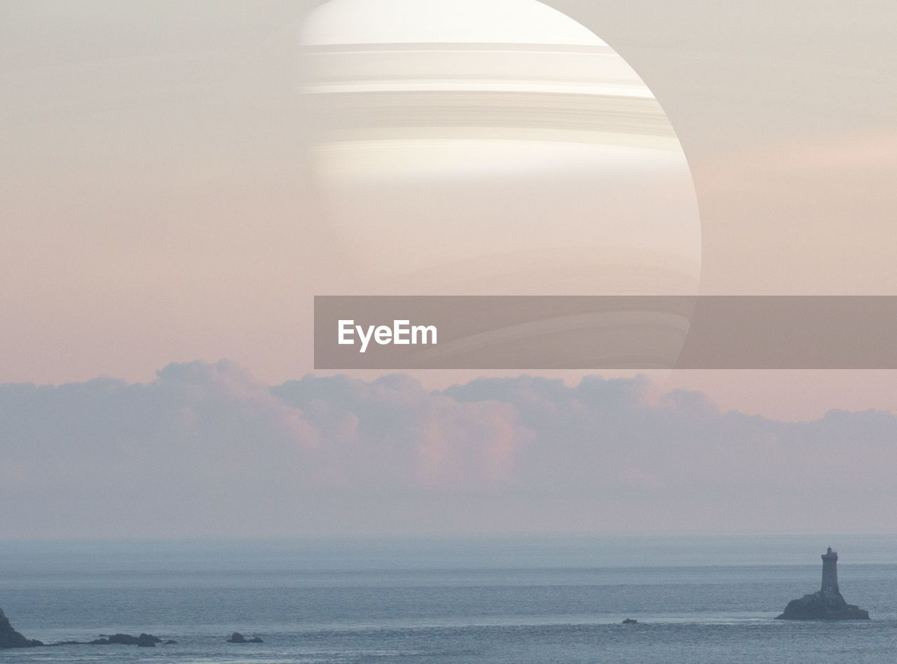 Scenic view of sea against sky during sunset with planet saturn