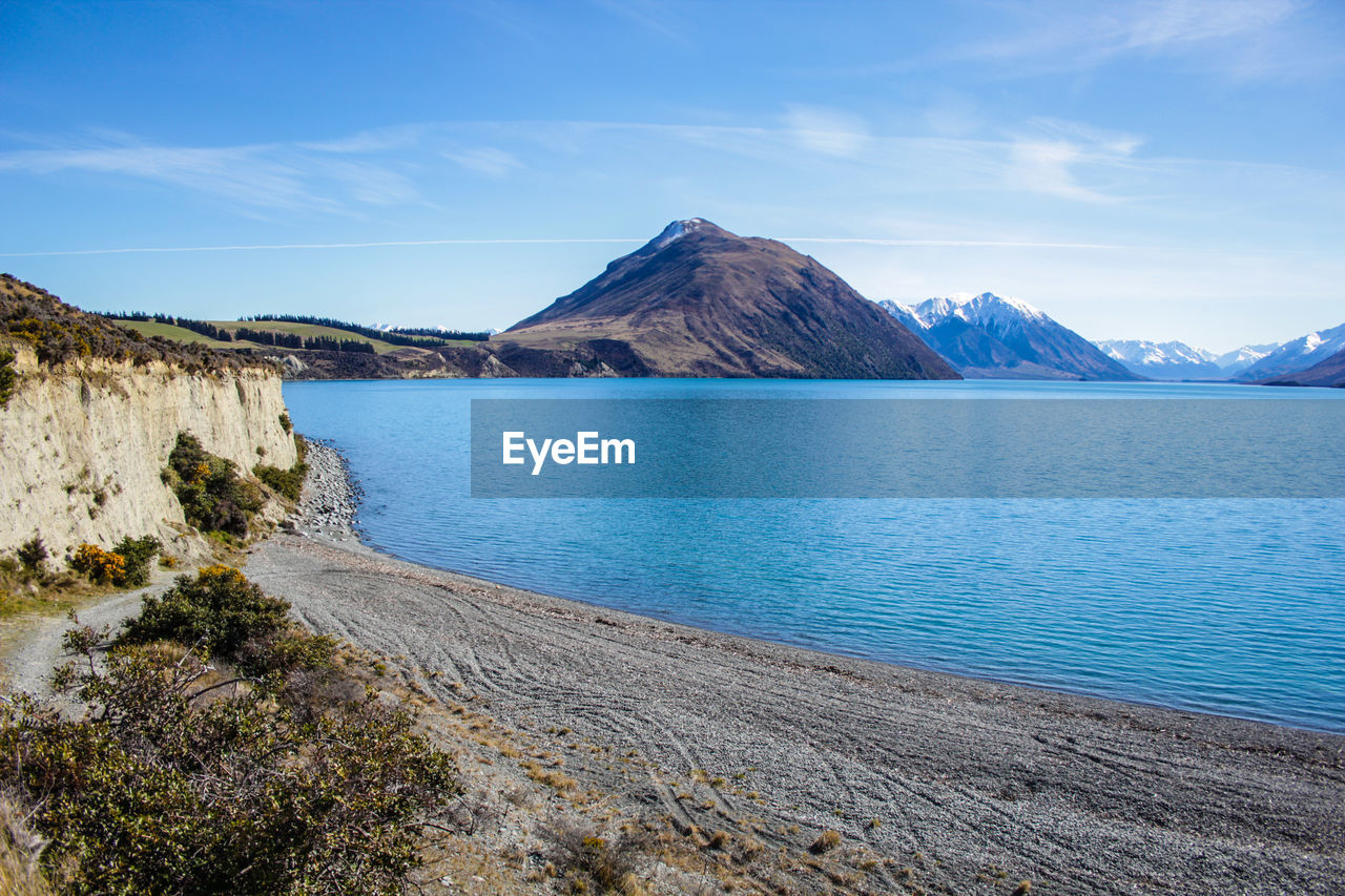 Scenic view of sea and mountains against blue sky