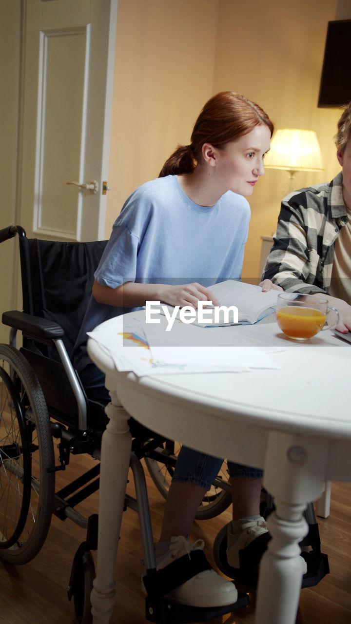 Young woman sitting on wheelchair at home