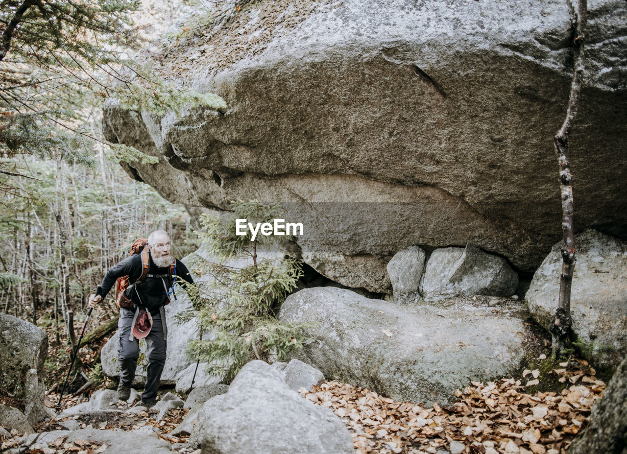 A retirement age male hikes beneath a boulder on the appalachian trail