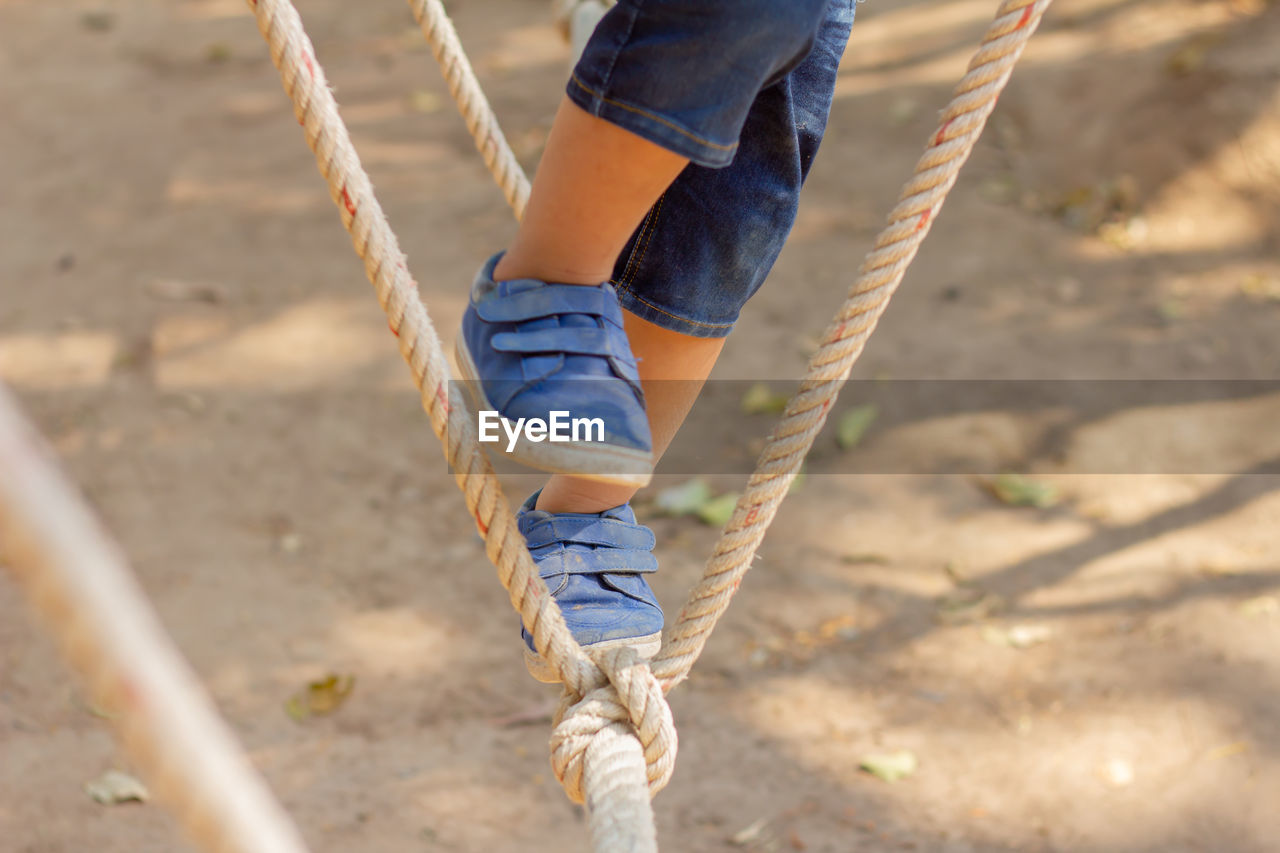 LOW SECTION OF PERSON ON SWING IN PLAYGROUND