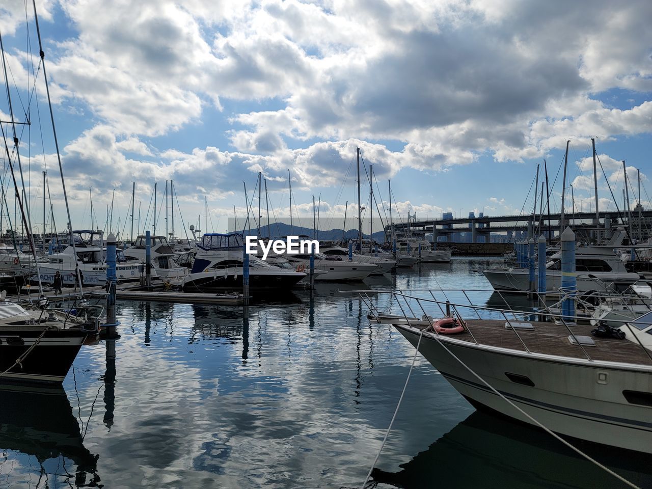 boats moored at harbor against cloudy sky