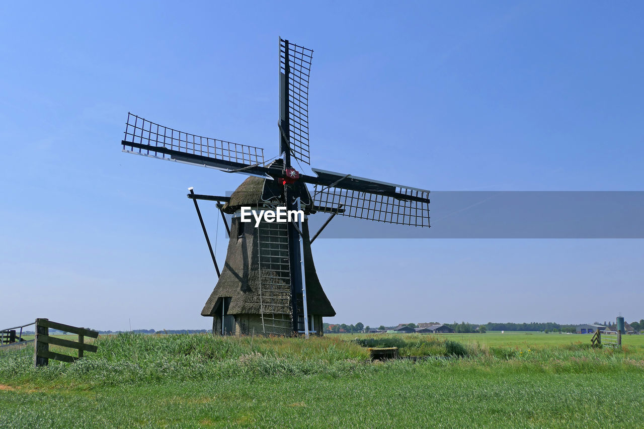 TRADITIONAL WINDMILL ON FIELD AGAINST SKY