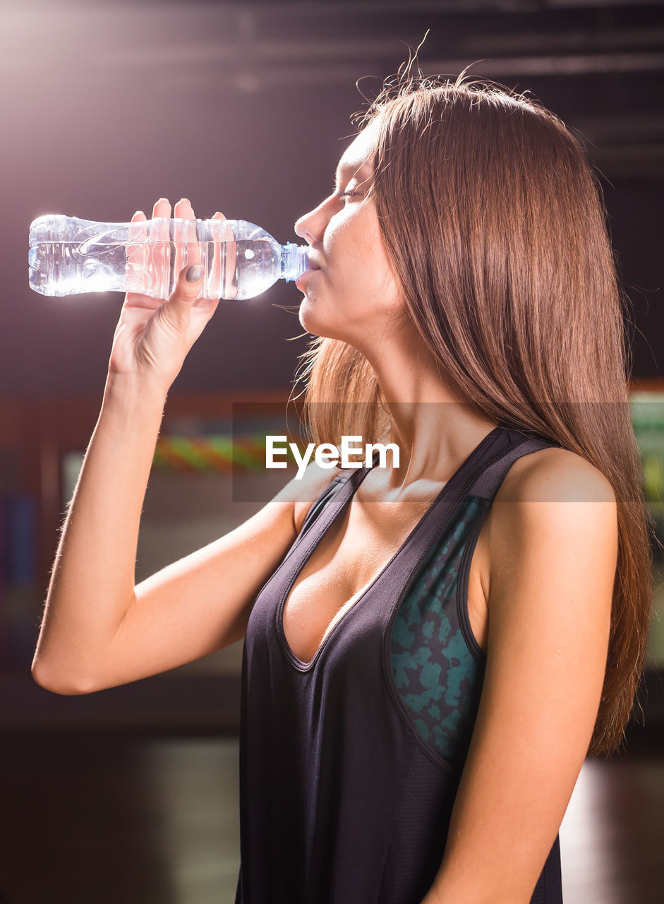 MIDSECTION OF WOMAN DRINKING GLASS WITH DRINK