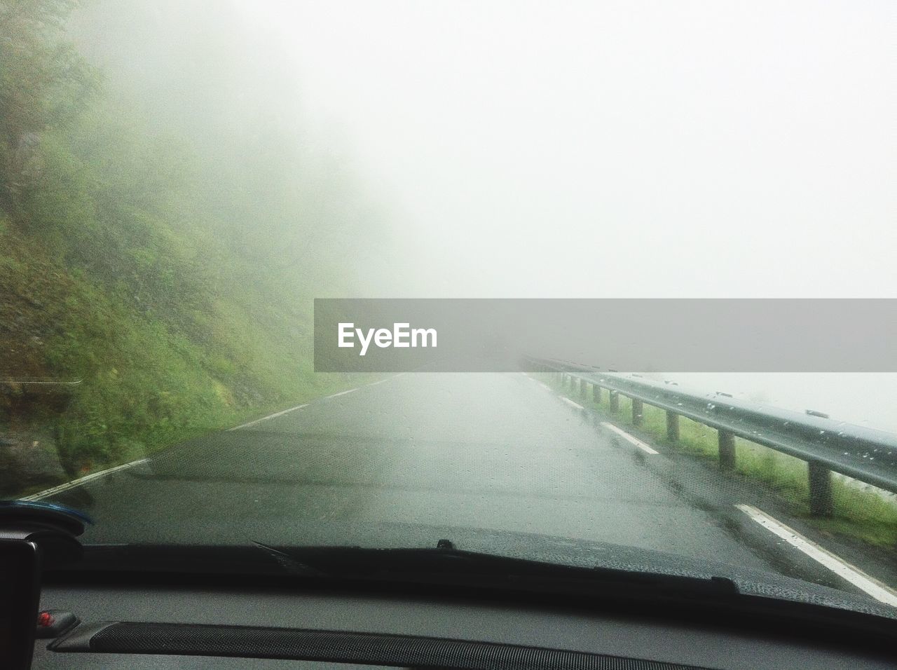 Road amidst trees against sky during foggy weather