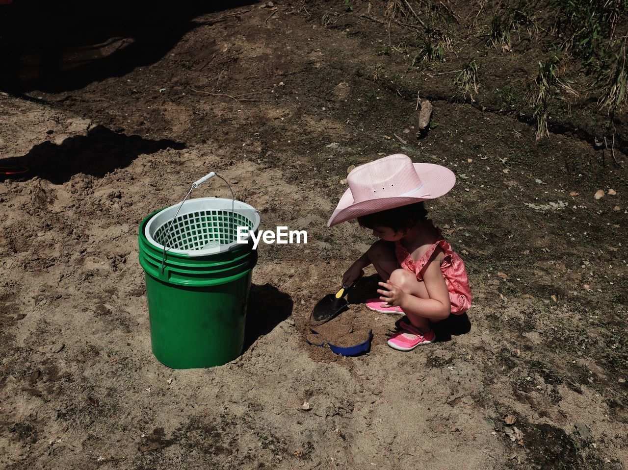 High angle view of girl playing at beach with shovel during sunny day