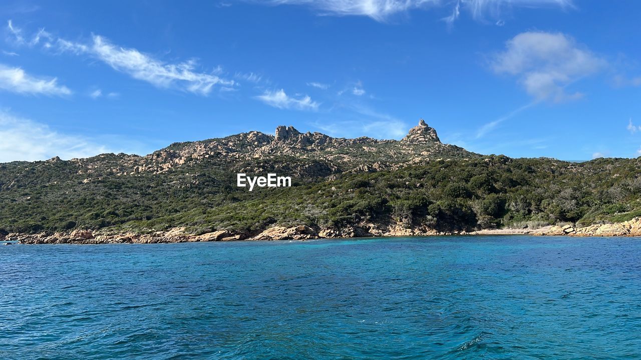 water, sky, scenics - nature, sea, land, beauty in nature, mountain, nature, blue, travel destinations, travel, landscape, body of water, environment, vacation, cloud, tree, no people, shore, tranquility, beach, coast, tranquil scene, tourism, island, islet, outdoors, bay, day, coastline, idyllic, plant, ocean, rock, architecture, non-urban scene, cove, trip, waterfront, holiday, horizon, forest, summer, sunny