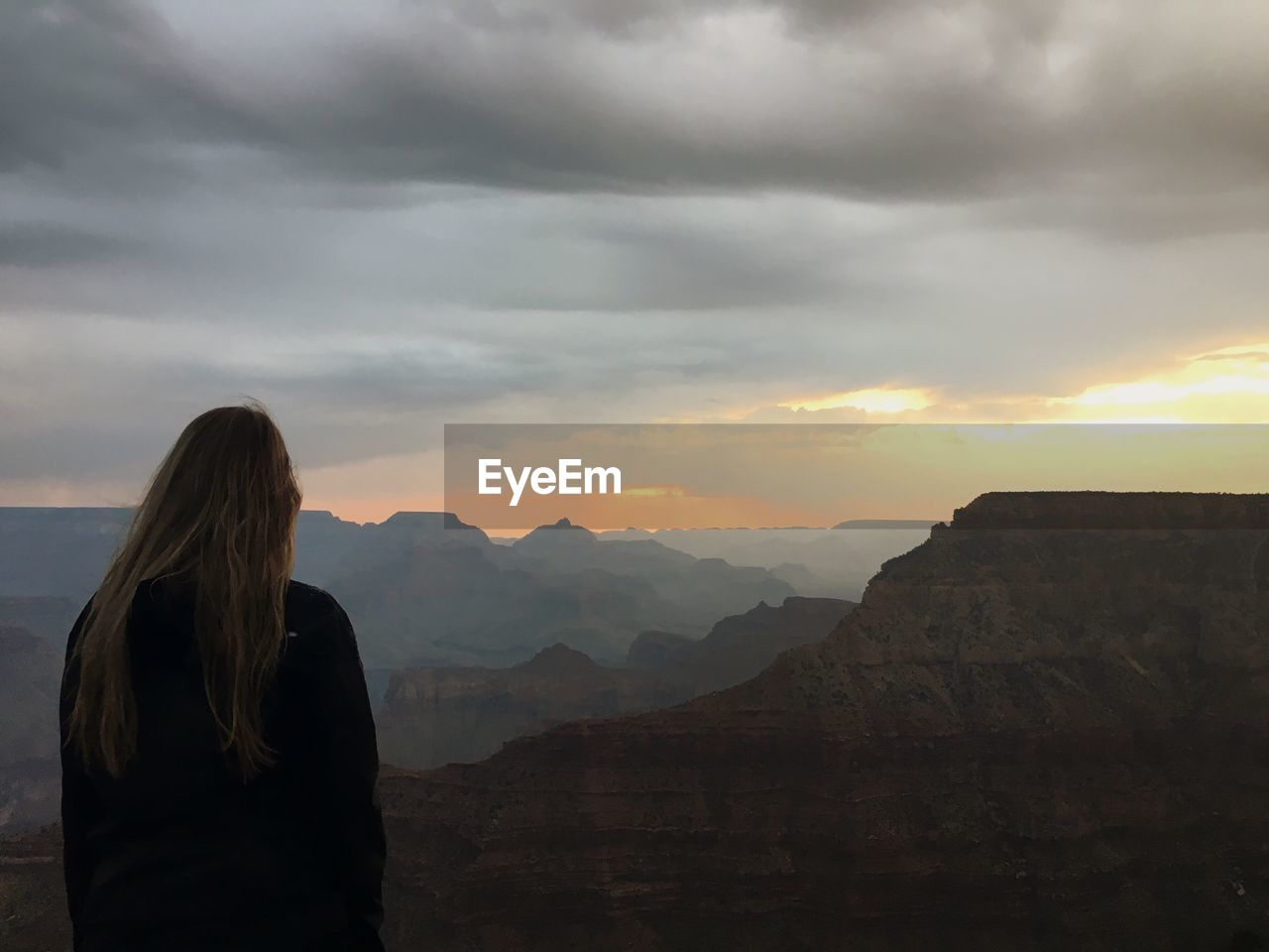 Rear view of woman standing on mountain against sky