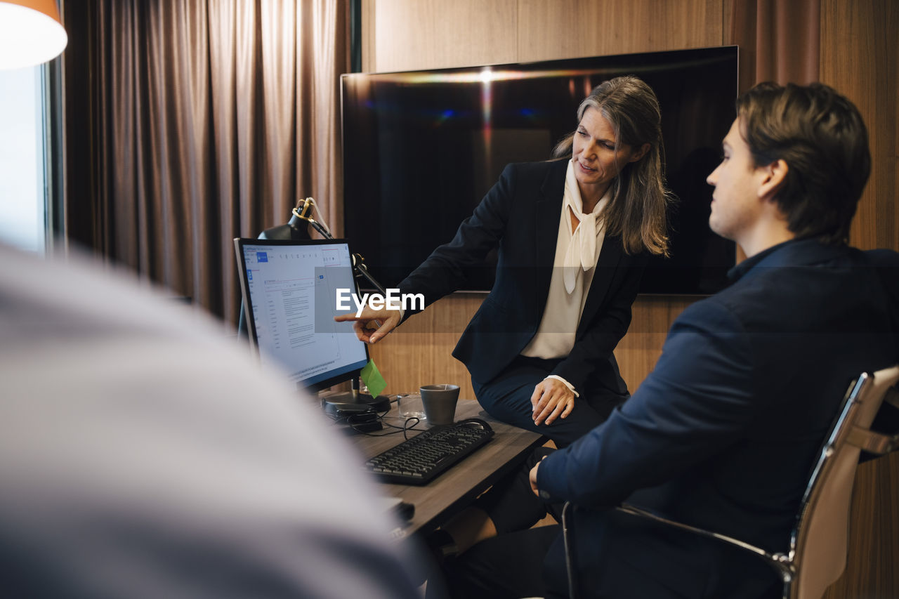 Female lawyer discussing over computer with male colleague at office