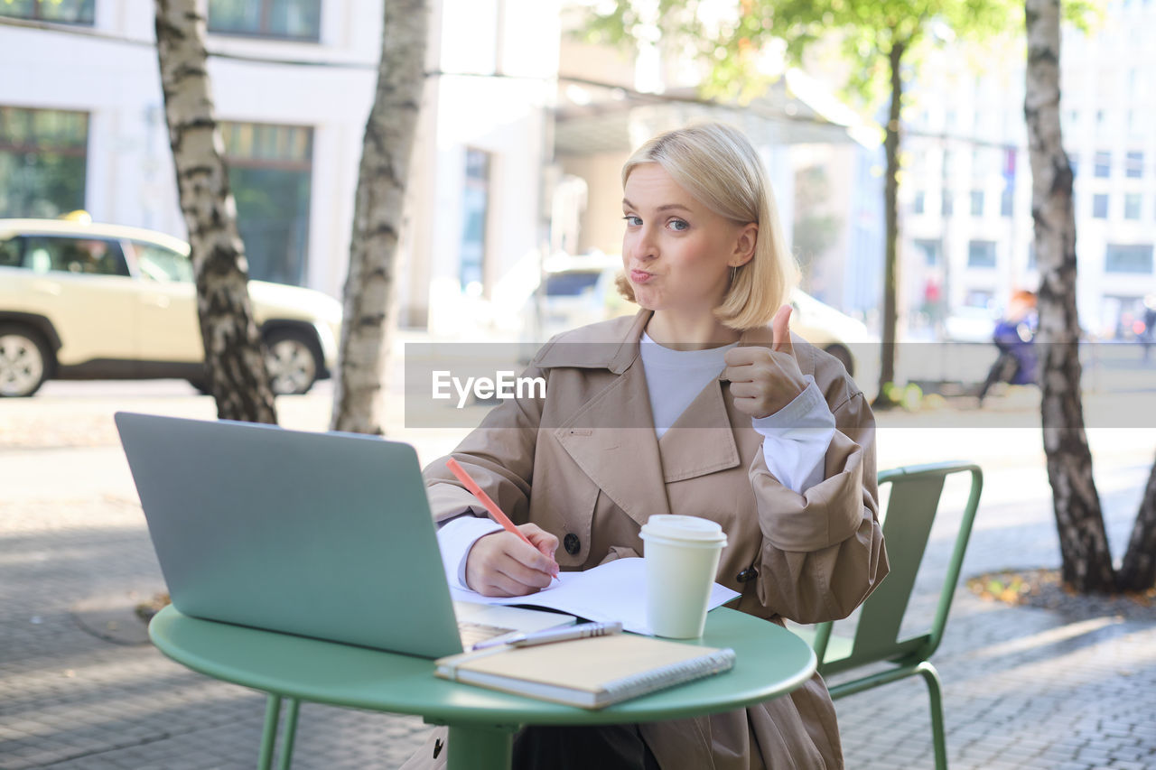 young woman using laptop while sitting on chair at cafe