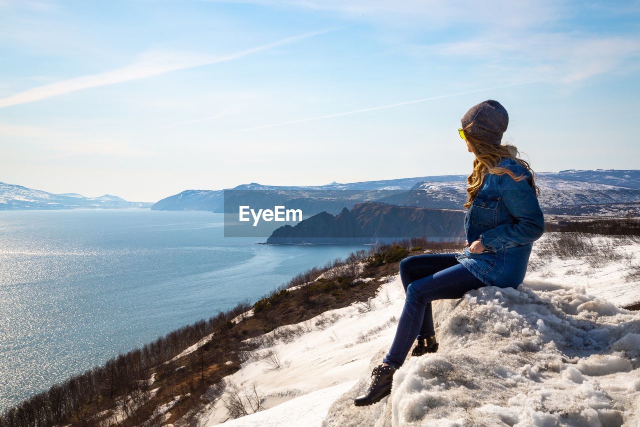 Woman on sitting on snow covered mountains against sky