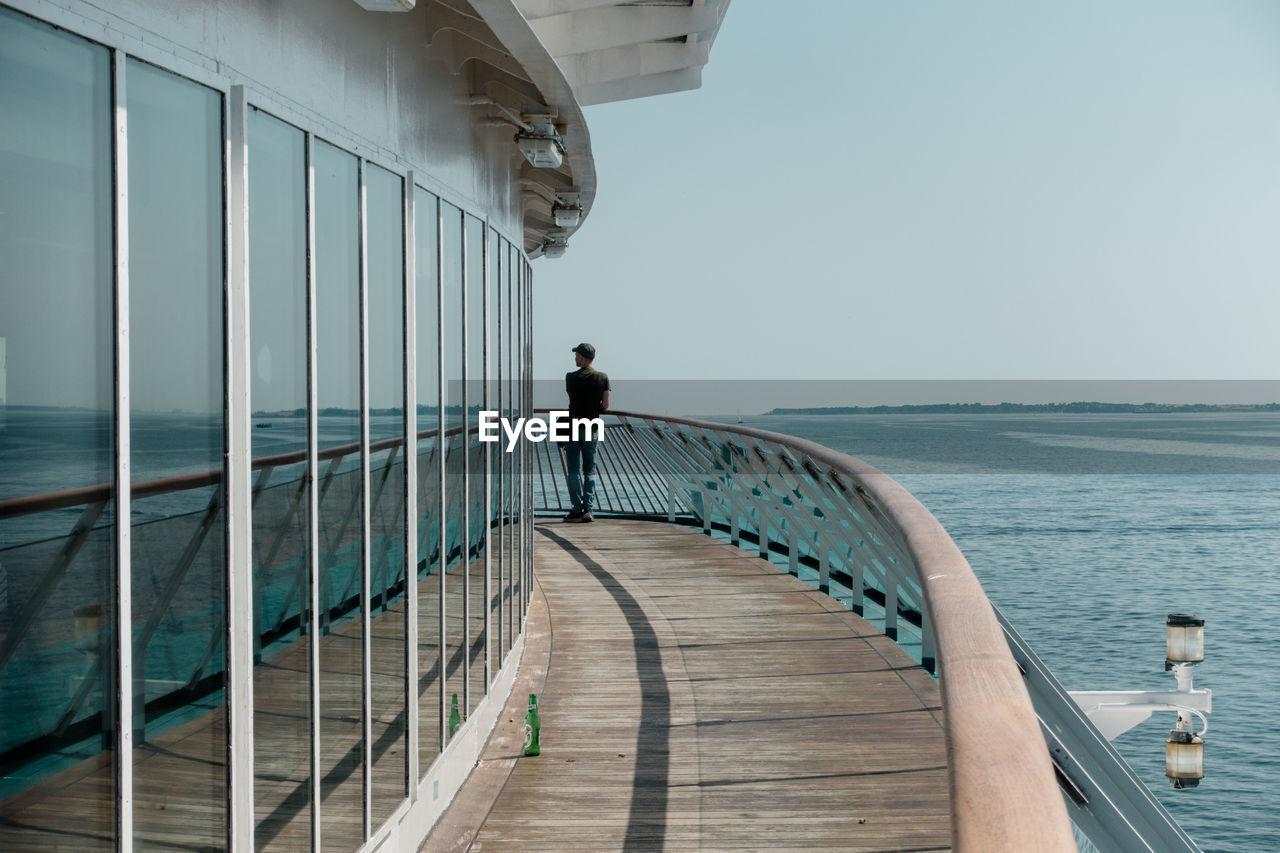 Rear view of man standing on cruise ship sailing in sea