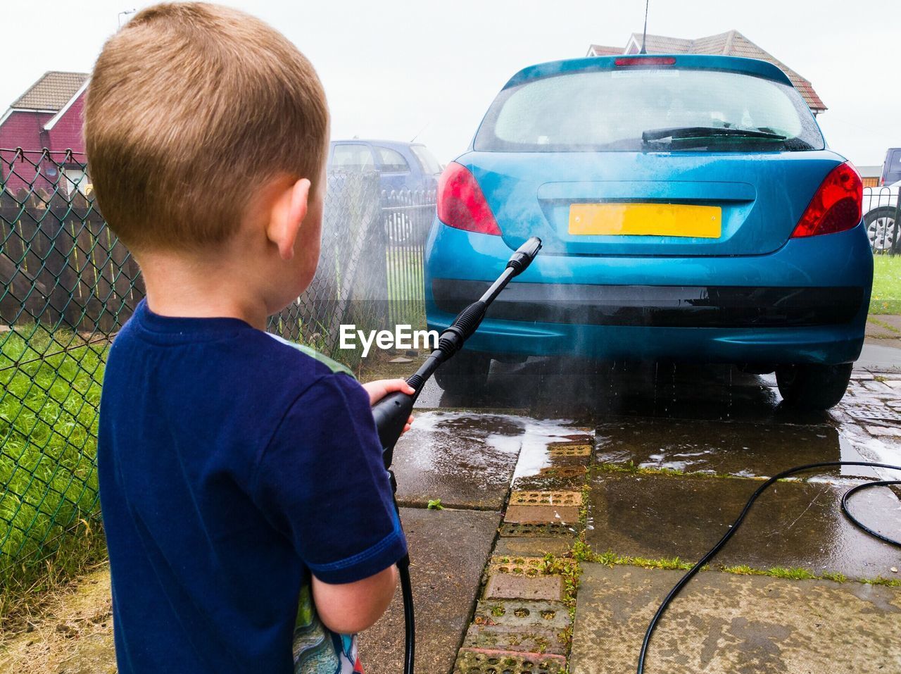 Rear view of boy washing car at yard