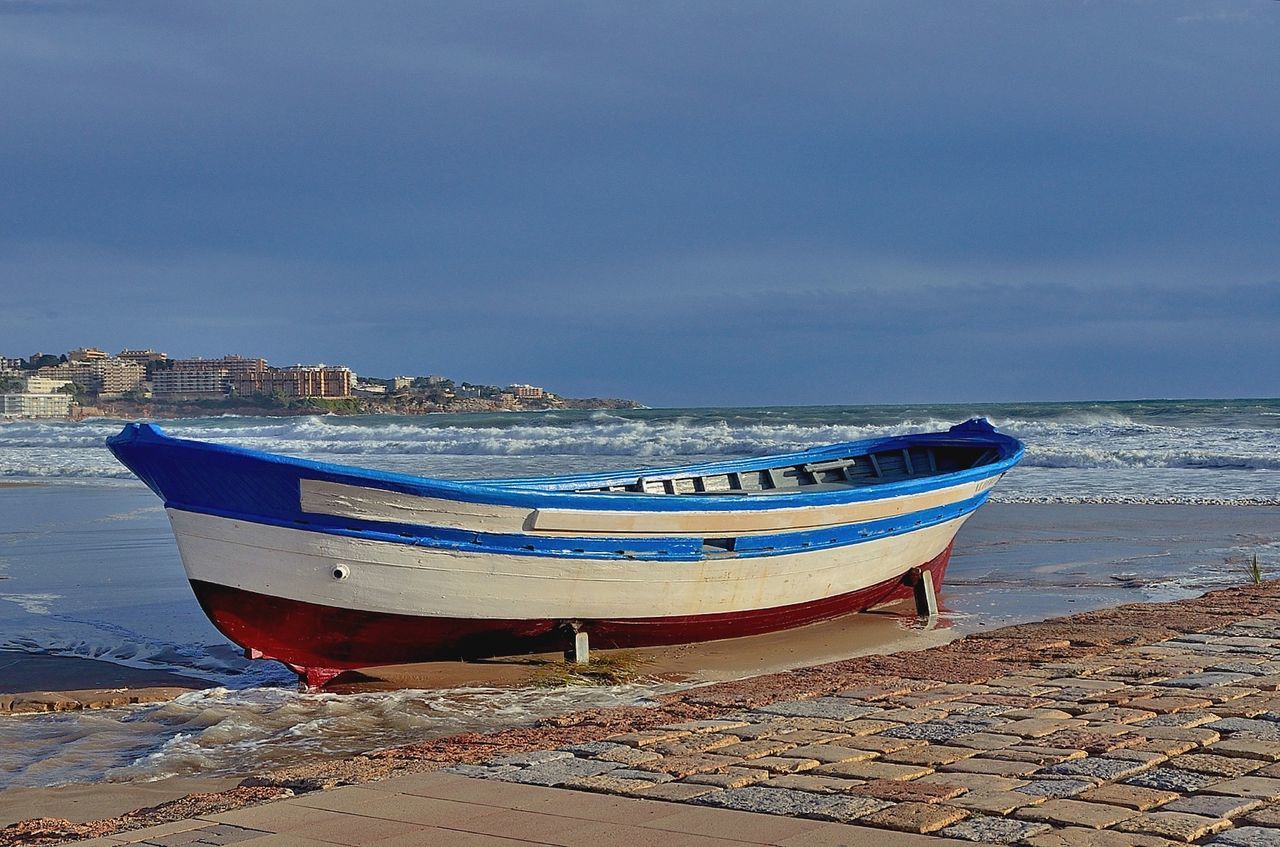 Boat moored on beach against sky