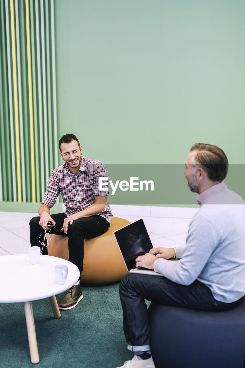 Happy businessmen conversing at modern office lobby