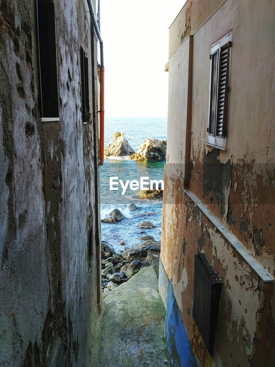 VIEW OF ABANDONED HOUSE BY SEA AGAINST SKY