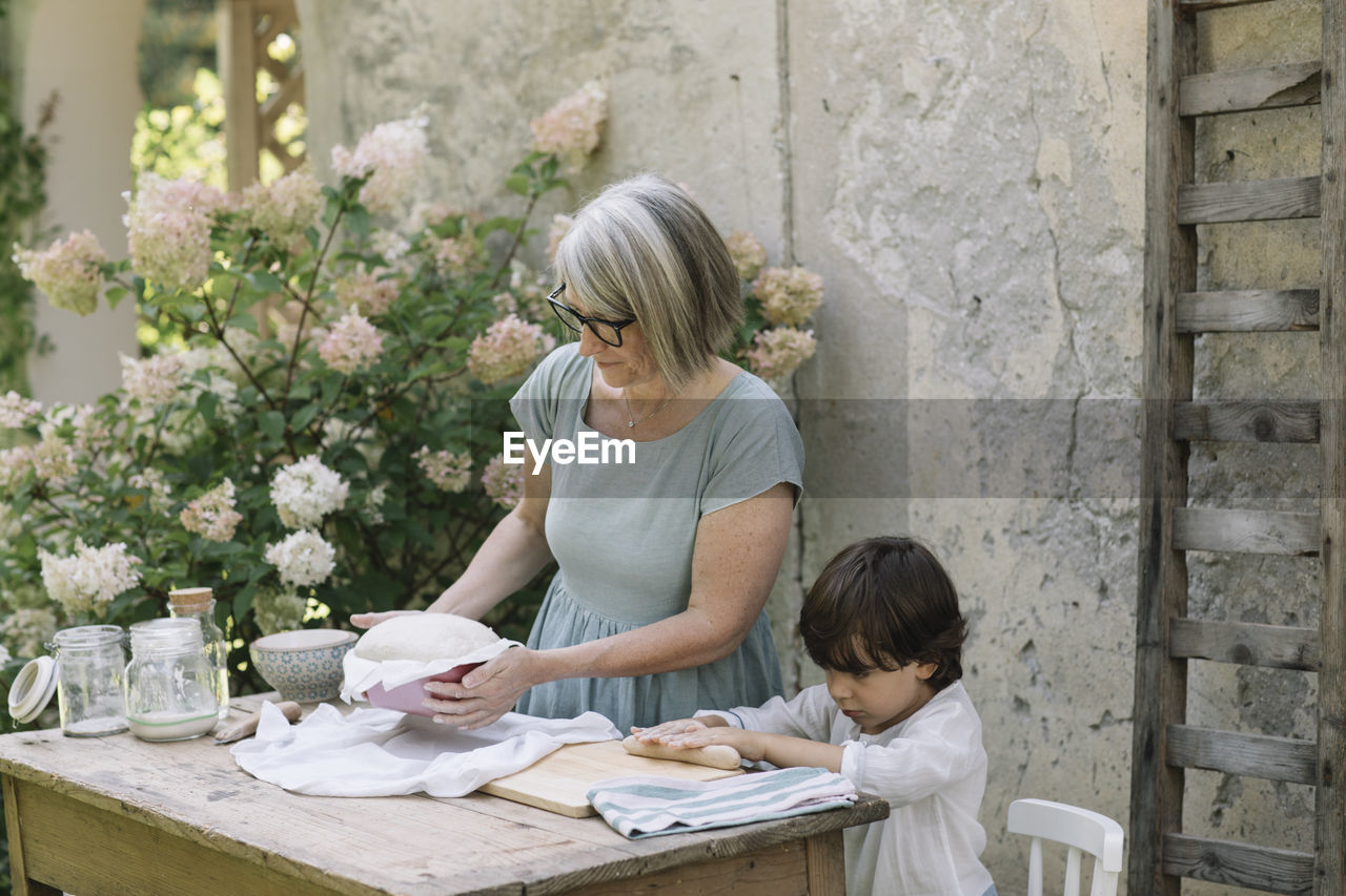 Cute boy with grandmother baking bread at back yard