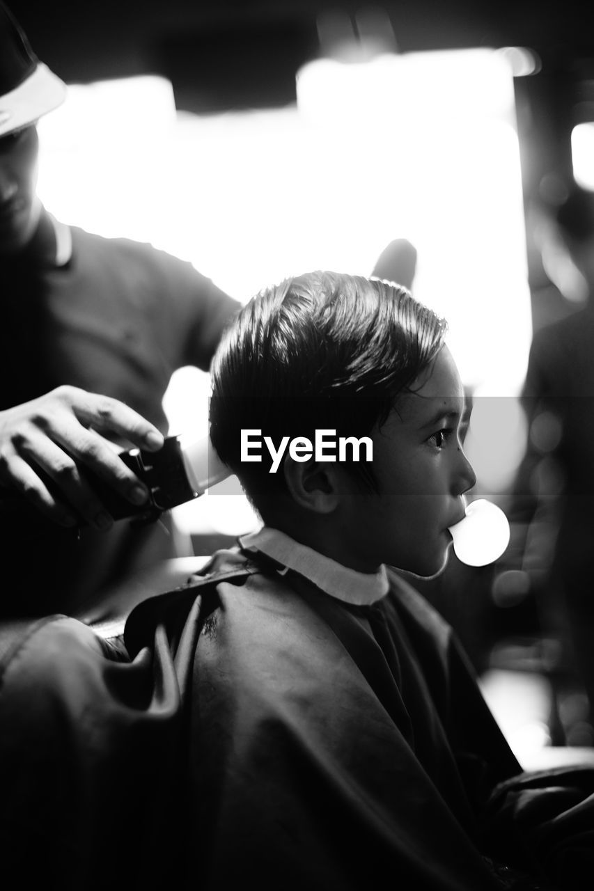 Barber cutting hair of boy at barber shop