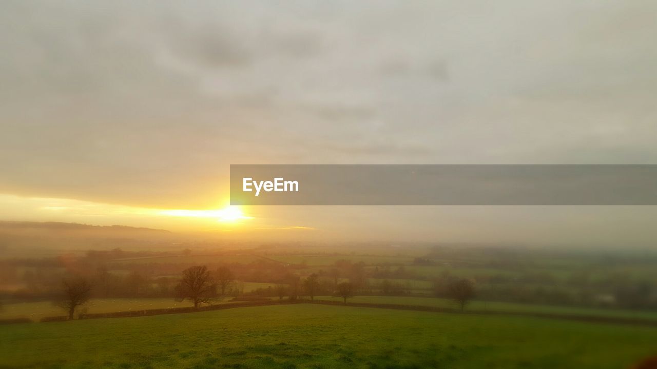 Scenic view of field against sky during sunrise