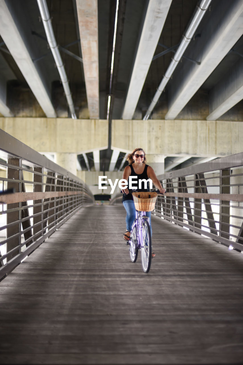 Full length of woman cycling on bridge