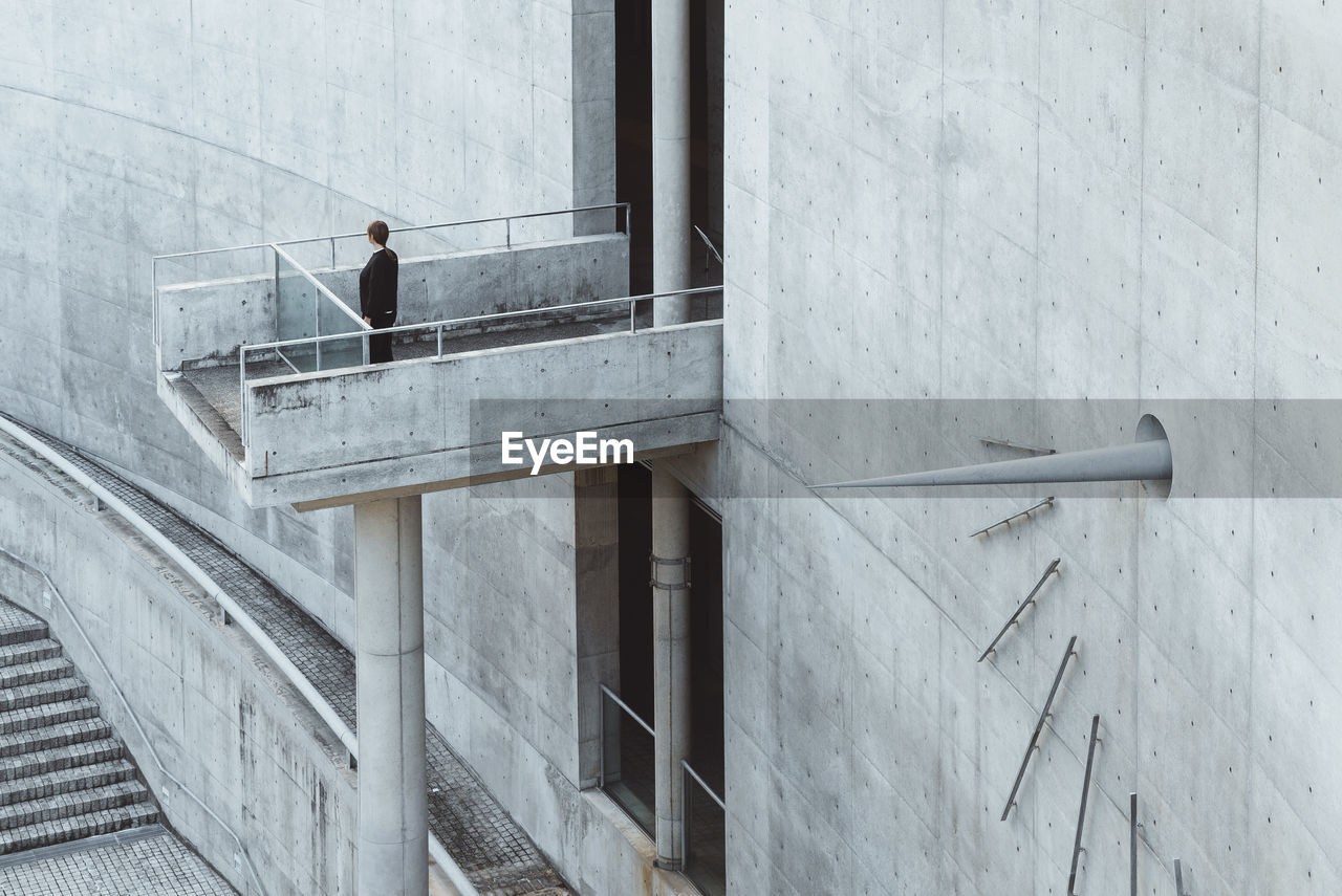 FULL LENGTH OF MAN STANDING BY WINDOW OF BUILDING