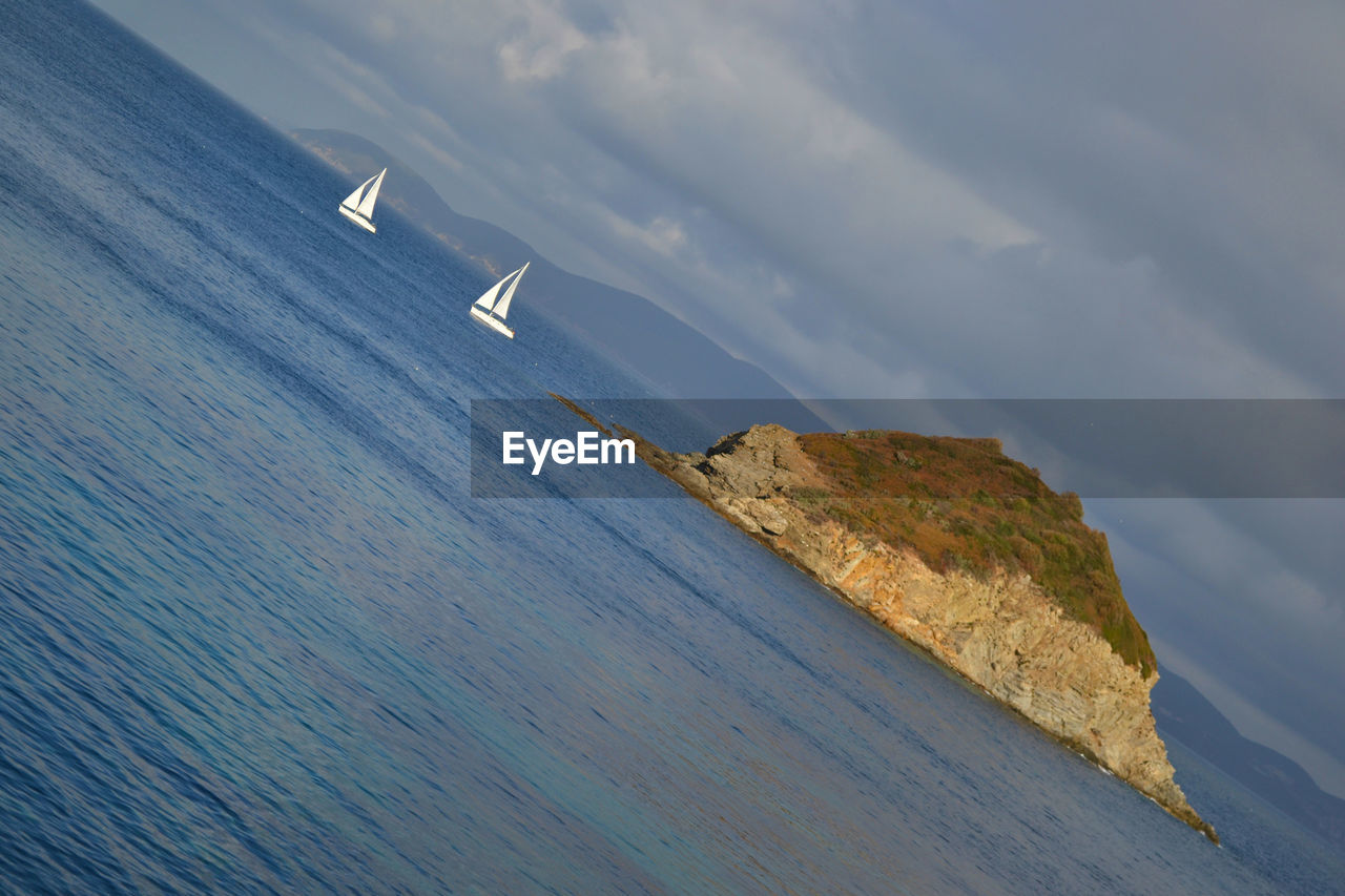 Rock formation on sea against cloudy sky