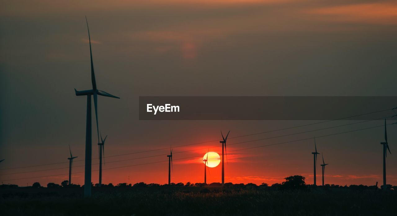 SILHOUETTE OF WIND TURBINES AT SUNSET