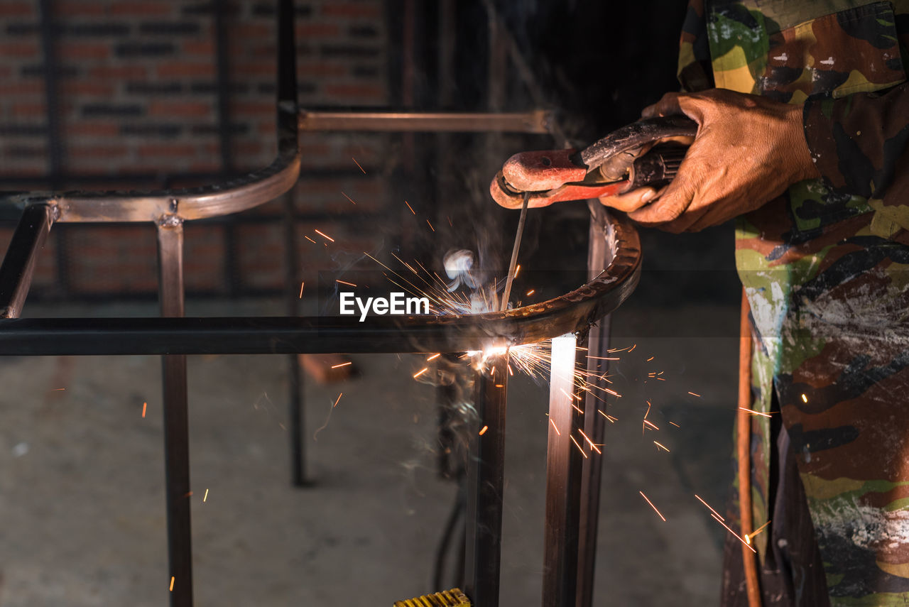 Midsection of worker welding metal in workshop