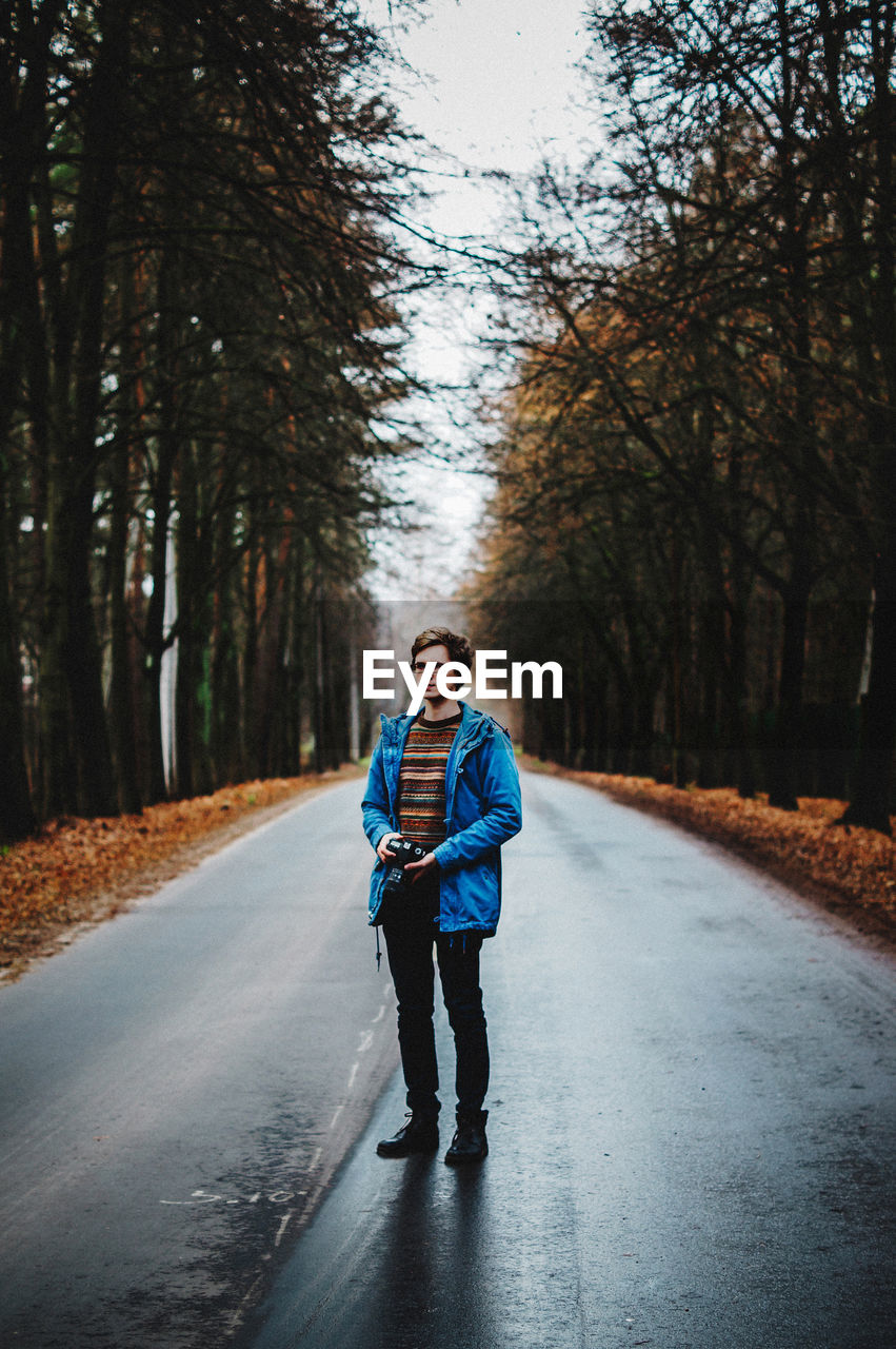 Full length of man standing on road amidst trees