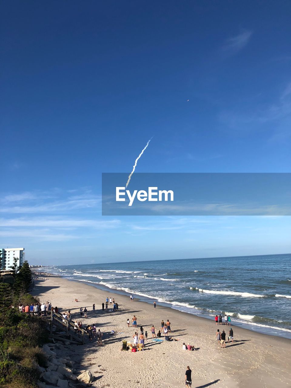 PEOPLE ON BEACH BY SEA AGAINST BLUE SKY