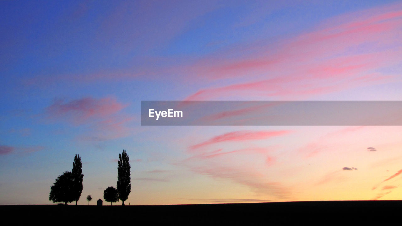 SCENIC VIEW OF SILHOUETTE FIELD AGAINST SKY AT SUNSET