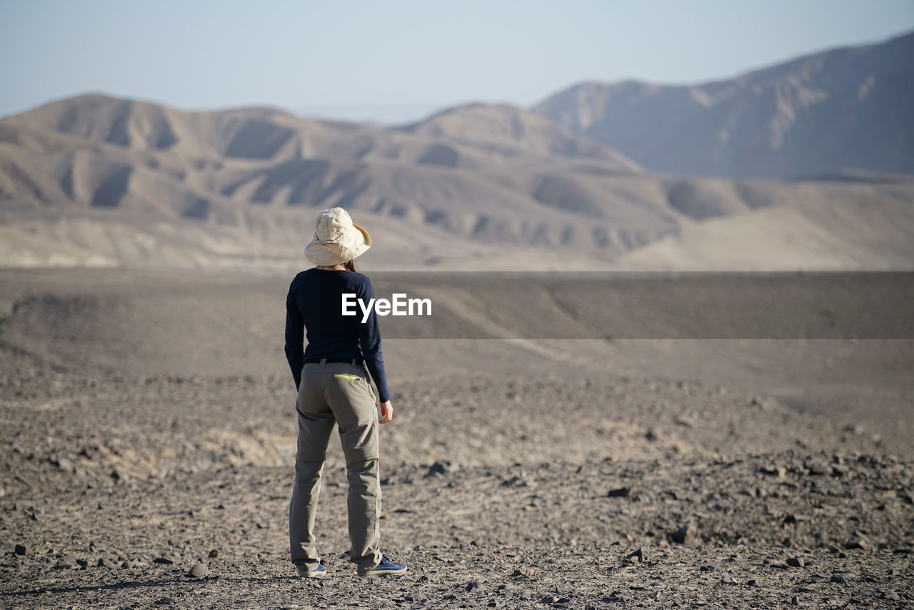 Rear view of mid adult woman standing on landscape