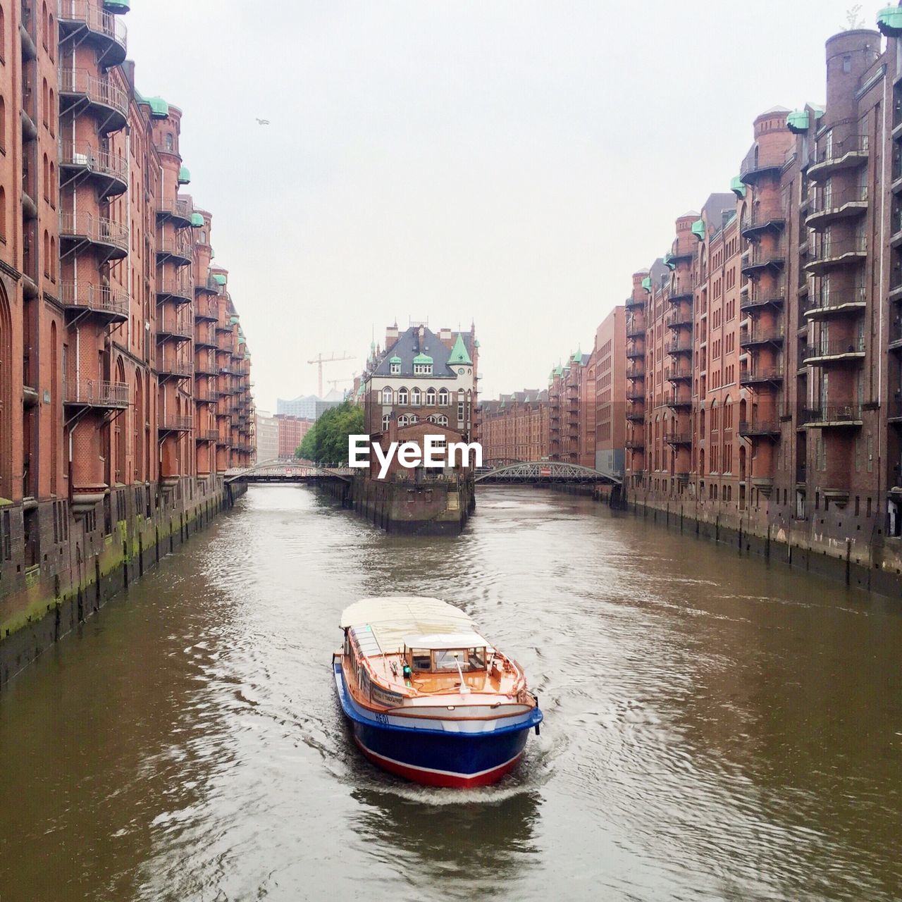 Passenger craft on elbe river amidst warehouses at speicherstadt